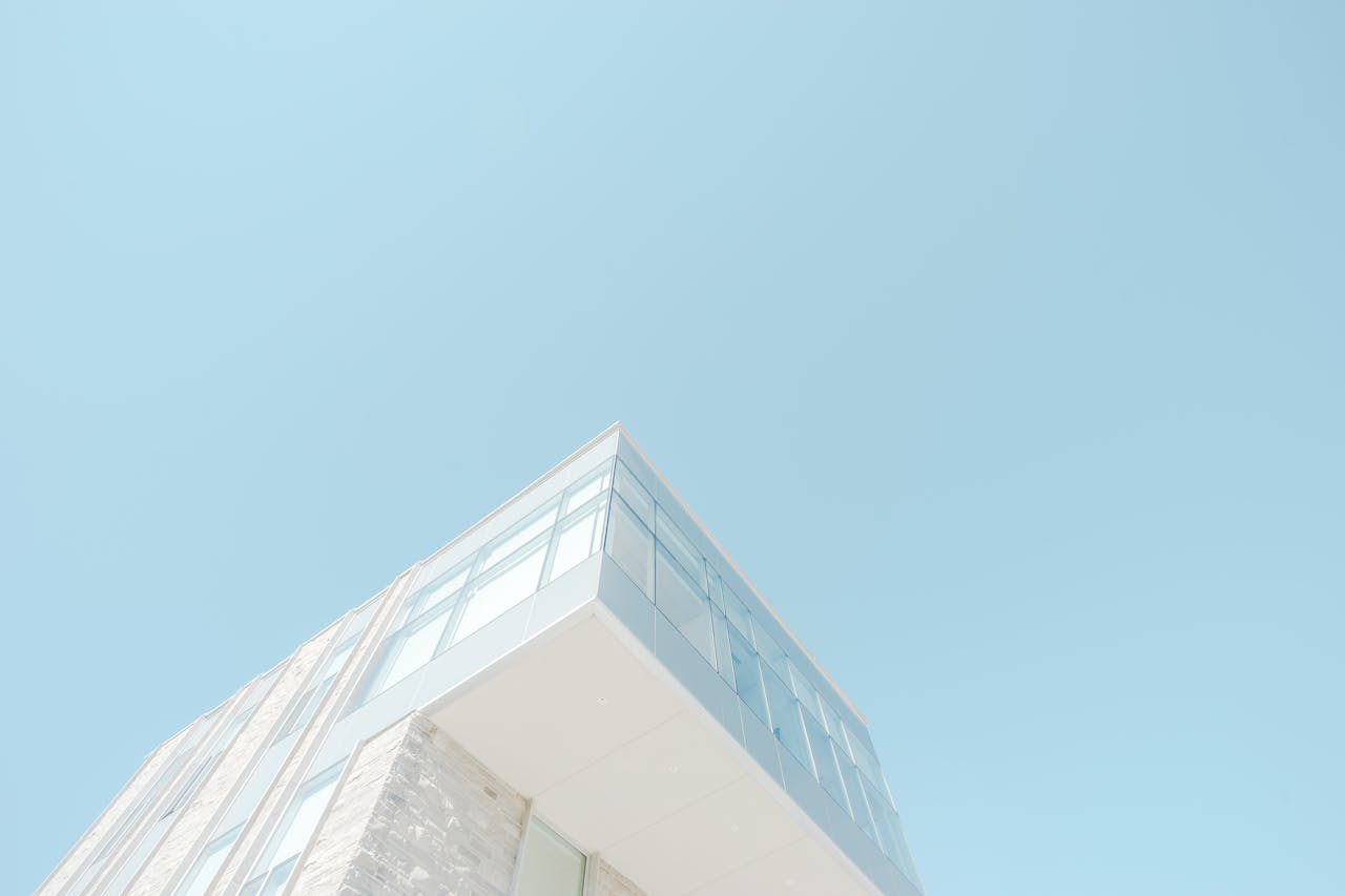 A low-angle shot of a modern building with a glass facade against a bright blue sky in London, Canada.